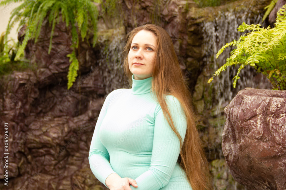beautiful young girl sits on stones near an artificial reservoir and waterfall beautiful young girl sits on stones near an artificial reservoir and waterfall