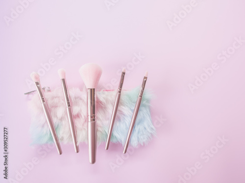 Beauty and Makeup concept from facial cosmetics, blush brush, brow brush, highlighter palette and eyeshadows with pink-tone for face make up on pink background. © TongTa