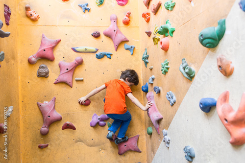 Boy climbing on artificial boulders wall in gym