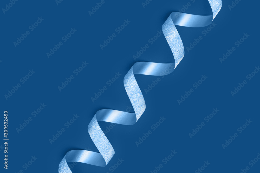 Silver spiral ribbon on classic blue background. Holiday greeting card trend color with copy space. Silver spiral ribbon on classic blue background. Holiday greeting card trend color with copy space.