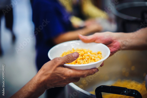 фотографія Food donation to the poor: The hands of the homeless are waiting to receive food from volunteers