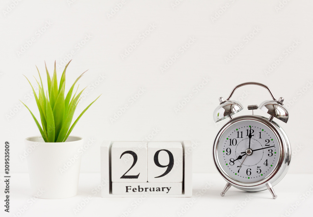 February 29 on a wooden calendar next to the alarm clock.Calendar date, holiday event or birthday.The last day of the winter month. February 29 happens every four years. - obrazy, fototapety, plakaty 