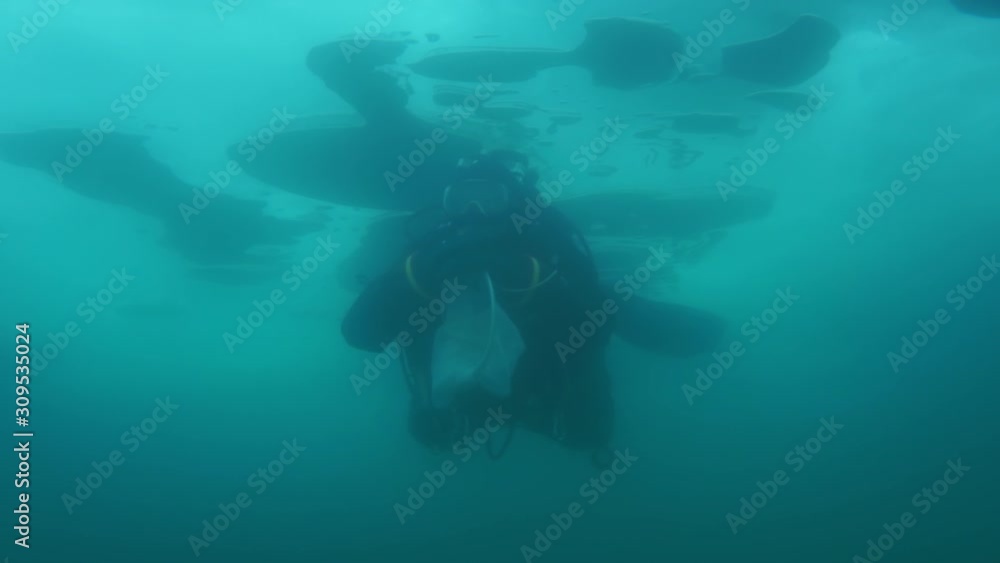 Researcher traveler diver underwater under ice on bottom of Lake Baikal in Siberia Of Russia. Researcher traveler diver underwater under ice on bottom of Lake Baikal in Siberia Of Russia.