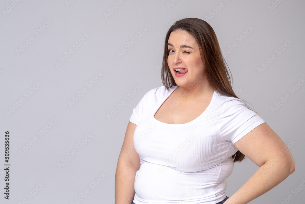 Plus Size Model with long hair posing in studio. Winks, blinks Plus Size Model with long hair posing in studio. Winks, blinks