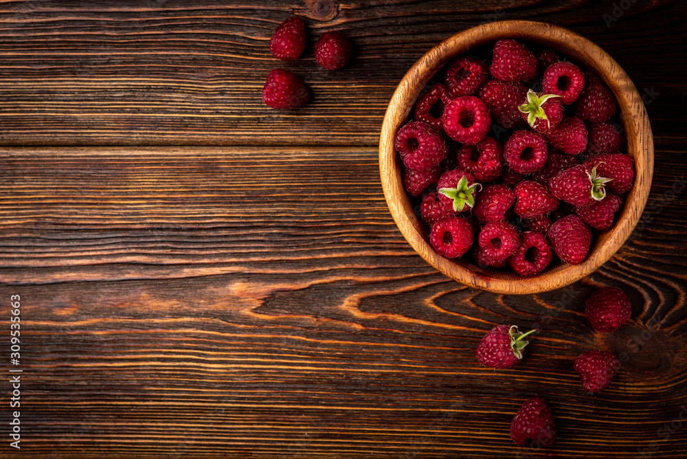 Fresh raspberry in wooden bowl on dark wooden background. Fresh raspberry in wooden bowl on dark wooden background.