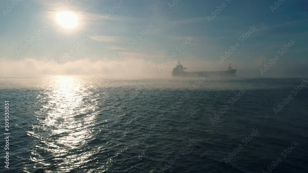 Aerial view of cargo container ship sails in sea fog, crane vessel working for delivery of delivery containers. Aerial view of cargo container ship sails in sea fog, crane vessel working for delivery of delivery containers.