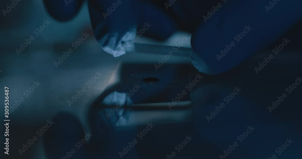 Scientist preparing a liquid sample on a glass plate for a microscope. Blue lighting in a laboratory.Slow motion, close up, shot with BMPCC 4K.Biochemistry, pharmaceutical medicine,science Scientist preparing a liquid sample on a glass plate for a microscope. Blue lighting in a laboratory.Slow motion, close up, shot with BMPCC 4K.Biochemistry, pharmaceutical medicine,science