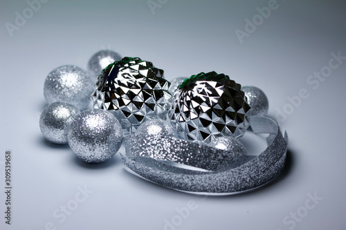 Macro abstract view of sparkling silver holiday baubles and ribbons on white background with copy space