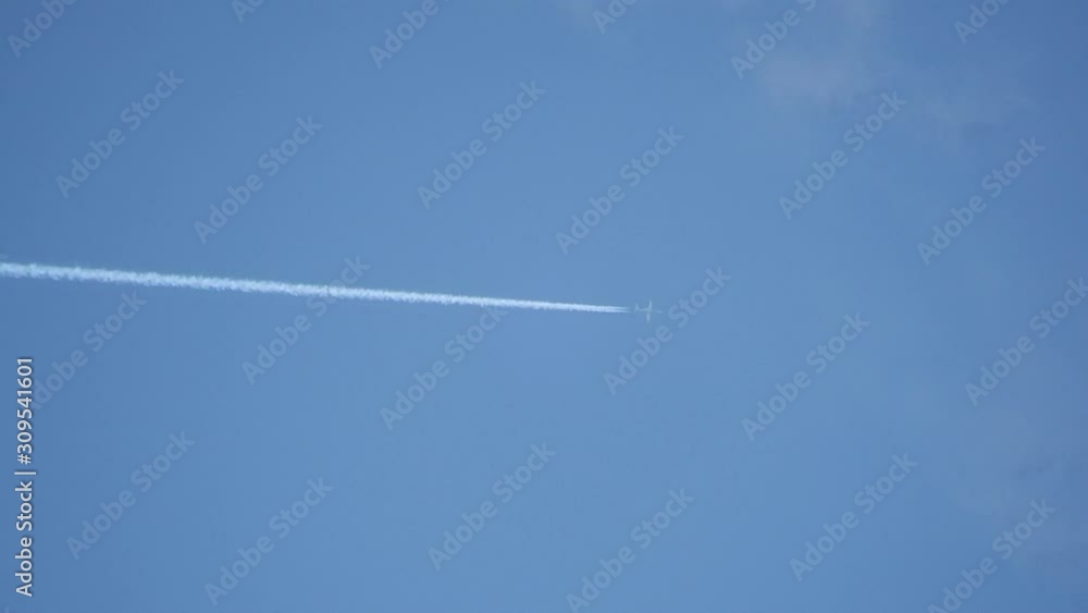 Closeup Of Jet Flying With Jet Stream Contrails In Blue Sky Through White Wispy Clouds Closeup Of Jet Flying With Jet Stream Contrails In Blue Sky Through White Wispy Clouds