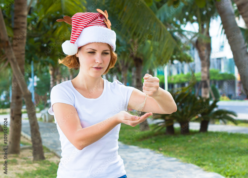 A young woman holds sand in her hands on her palm, spills sand from hand to hand on an hourglass, time. Girl in santa hat shows that time is running out. Merry christmas and a happy new year A young woman holds sand in her hands on her palm, spills sand from hand to hand on an hourglass, time. Girl in santa hat shows that time is running out. Merry christmas and a happy new year