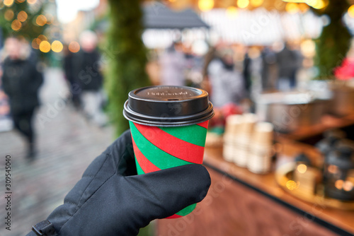 Christmas Market in European small city. Red and green Christmas Cup with mulled wine.