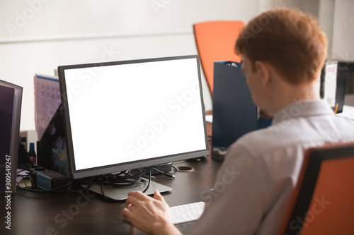Rear side view employee working on computer sitting at workplace