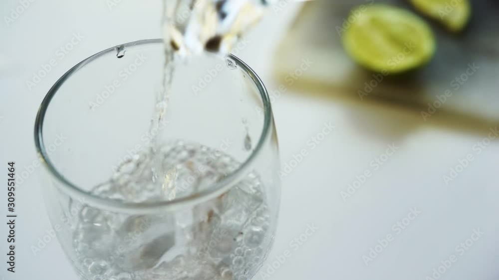 Close up slow motion pouring tasty sweet lime soda into water glass in white background Close up slow motion pouring tasty sweet lime soda into water glass in white background
