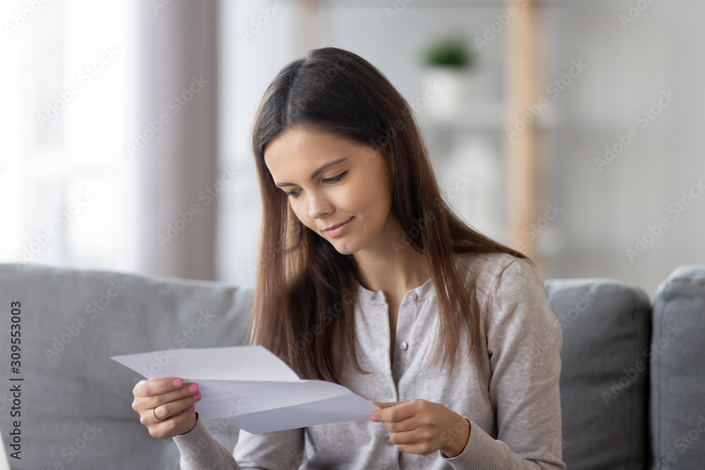 Young woman sit on couch reading paper letter Young woman sit on couch reading paper letter