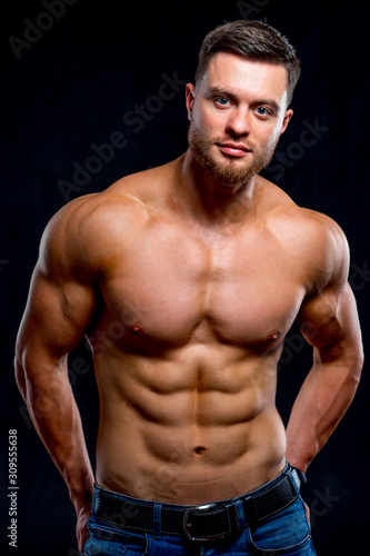 Portrait of strong healthy handsome athletic man fitness model isolated on dark background. Looking to the camera. Closeup.