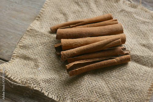 Cinnamon stick on rug sack on wooden background.