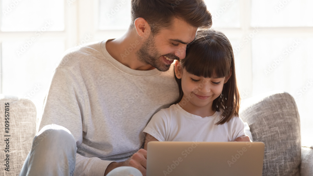 Loving father teaching little daughter to use laptop at home Loving father teaching little daughter to use laptop at home