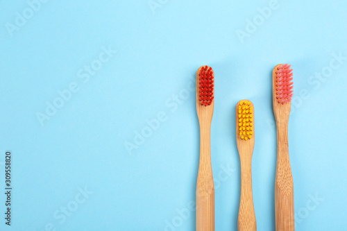 Toothbrushes made of bamboo on light blue background  flat lay. Space for text