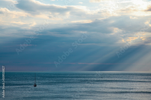 yacht in the sea rays from clouds landscape photo