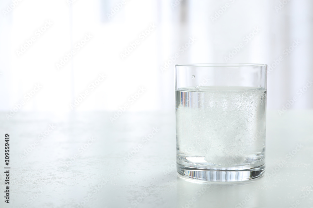 Woman putting tablet into glass of water indoors, space for text Woman putting tablet into glass of water indoors, space for text