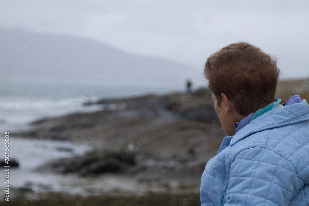 lonely senior woman looking at the sea from the coast
