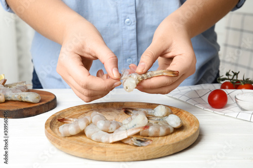 Woman peeling fresh shrimp at table, closeup