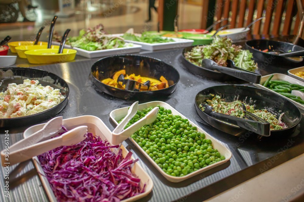 The salad buffet bar at the restaurant with lots of vegetables dishes.