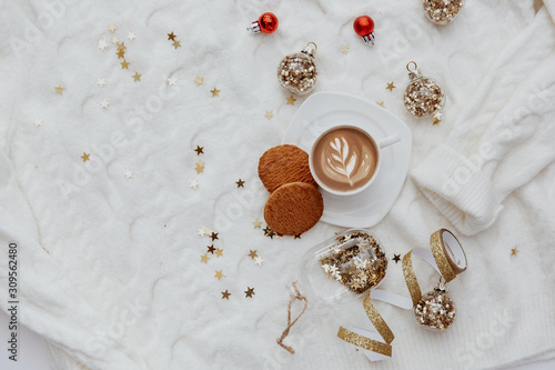 Hot coffee, christmas decorations and cookies over oversize warm sweater. Minimal blogger background
