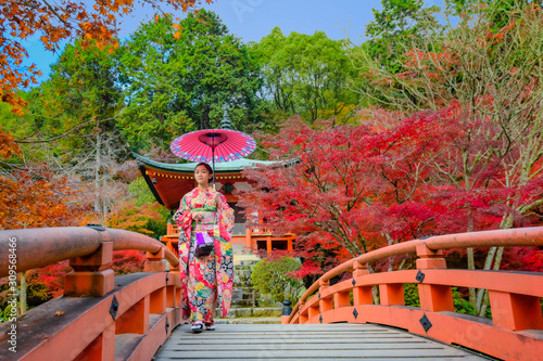 woman in old fashion style wearing traditional or original Japanese dressed  walks alone on the wooden bridge in garden park  japan old fashion style attractive in autumn season change