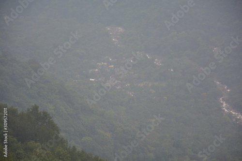 The fog on the hills of Cherrapunjee with trees and a stream flowing as seen from Eco Park, selective focusing © RUPAK