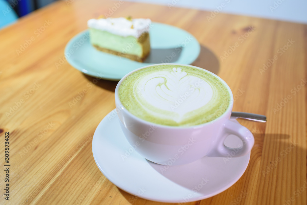 Matcha latte and pistachio cheesecake on a large bright wooden table Matcha latte and pistachio cheesecake on a large bright wooden table