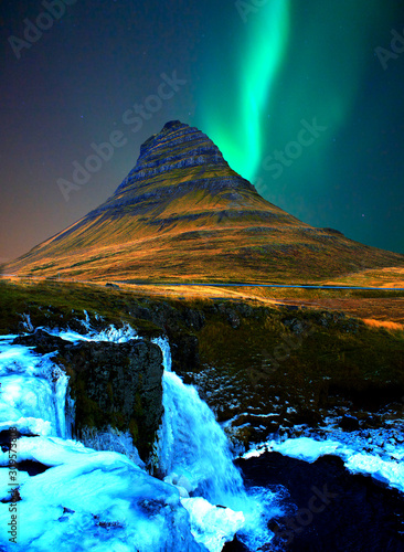 Iceland famous mountain Kirkjufell with aurora borealis Northern Light with waterfall in winter at night the best photo