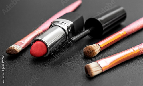 Makeup brushes with lipstick and mascara brush on black.