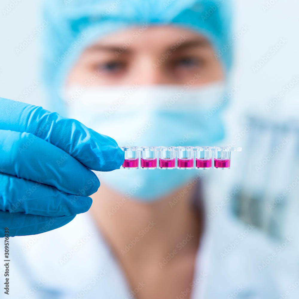lurred Woman in mask and latex gloves preparing pink samples for machine testing lurred Woman in mask and latex gloves preparing pink samples for machine testing