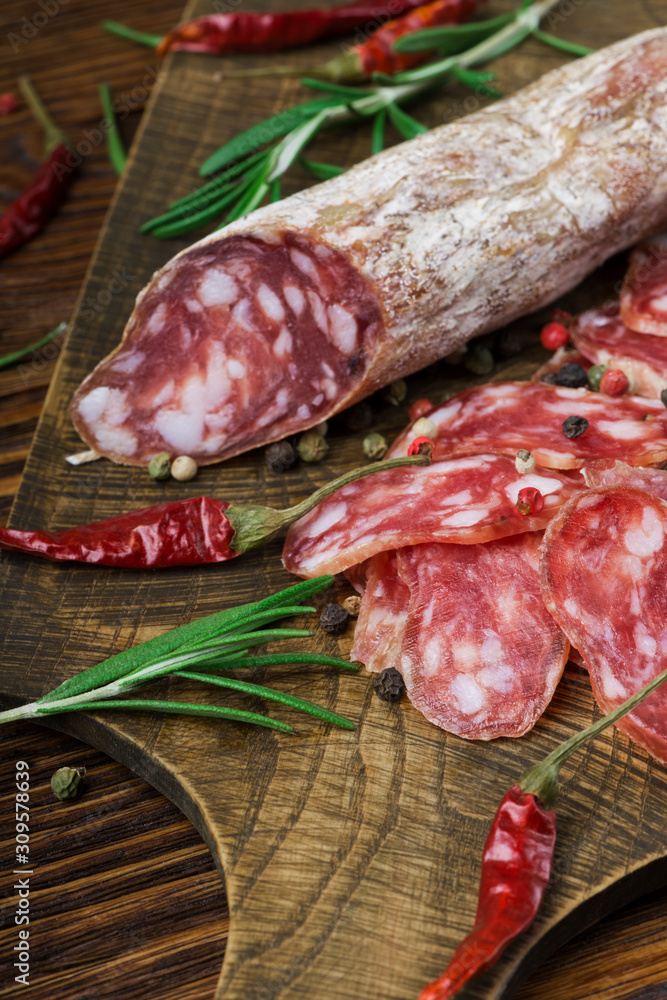 Italian salami with pepper and rosemary on a wooden board Italian salami with pepper and rosemary on a wooden board
