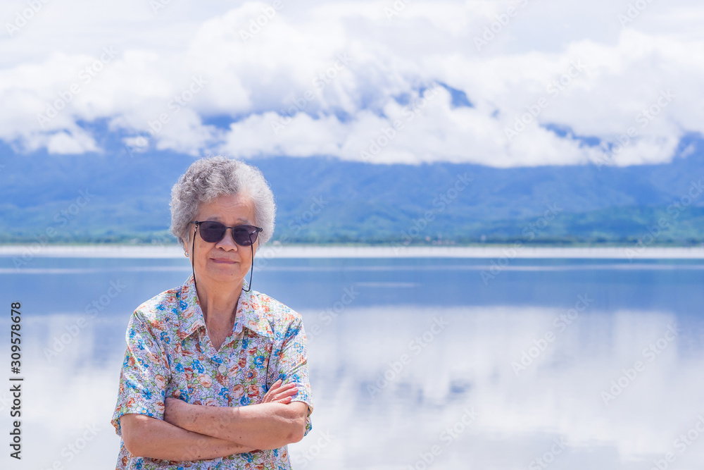 Senior woman standing and smile at side the lake