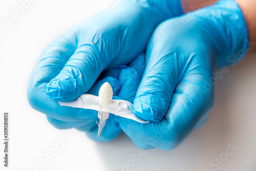 A gloved doctor opens suppositories for anal or vaginal use. Medical candles for the treatment of Candida, thrush, hemorrhoids, inflammation and fever. Effective drug on a white background photo