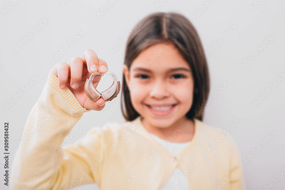 advertising hearing aid for children, a mixed race child shows a hearing aid. Children's hearing treatment advertising hearing aid for children, a mixed race child shows a hearing aid. Children's hearing treatment
