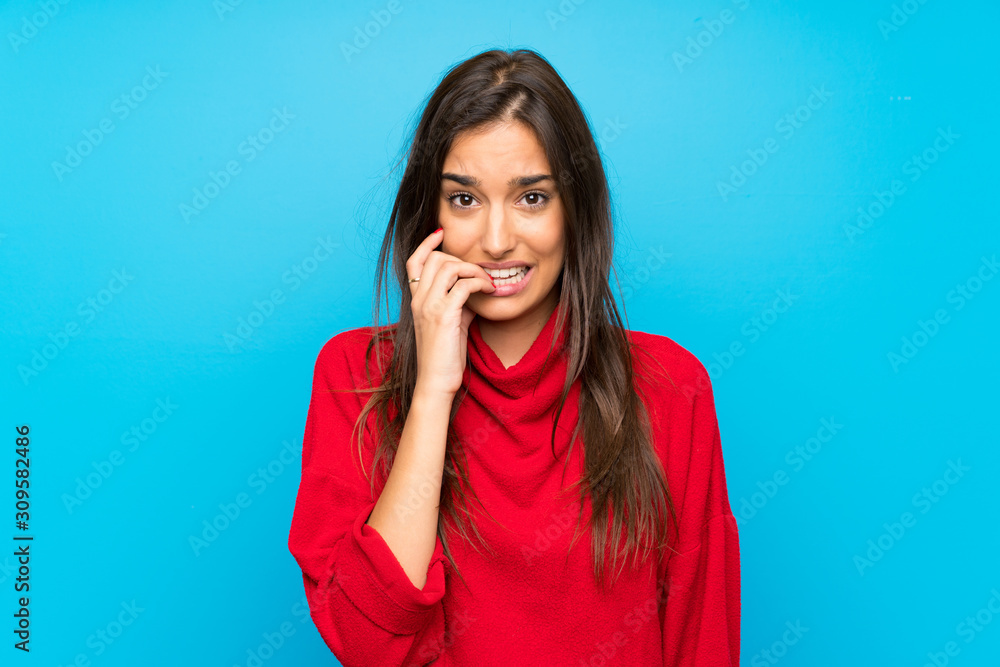 Young woman with red sweater over isolated blue background nervous and scared Young woman with red sweater over isolated blue background nervous and scared