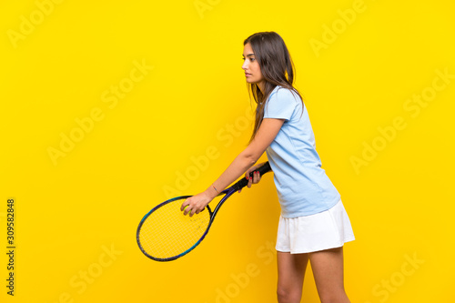 Young tennis player woman over isolated yellow wall © luismolinero