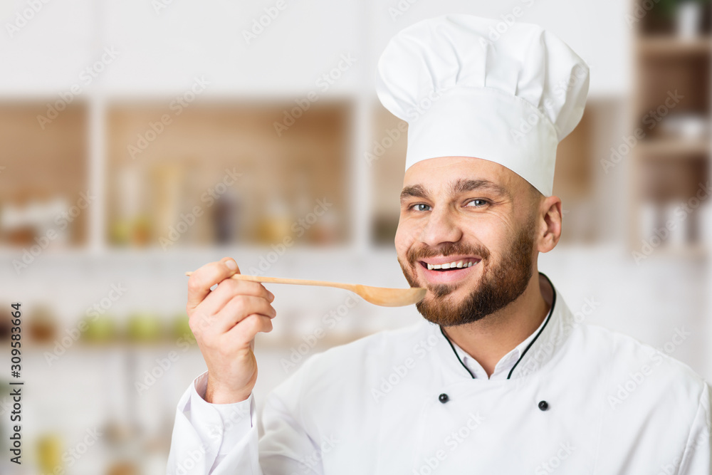 Smiling Chef Man Tasting Food Holding Spoon In Restaurant Kitchen Smiling Chef Man Tasting Food Holding Spoon In Restaurant Kitchen