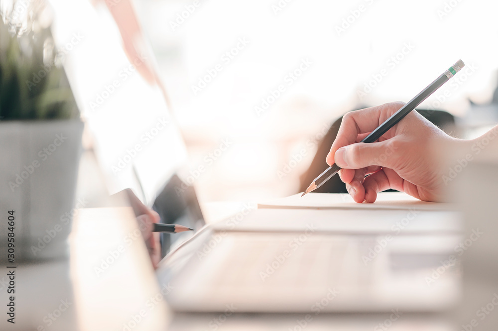 Closeup view of man hand writing on notebook with pencil.