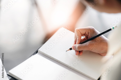 Closeup view of man hand writing on notebook with pencil. Copy space.