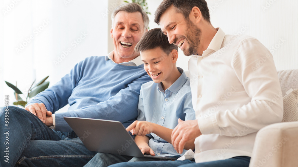Boy Using Laptop Sitting Between Father And Grandpa At Home Boy Using Laptop Sitting Between Father And Grandpa At Home