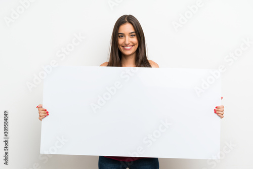 Young woman over isolated white background holding an empty white placard for insert a concept