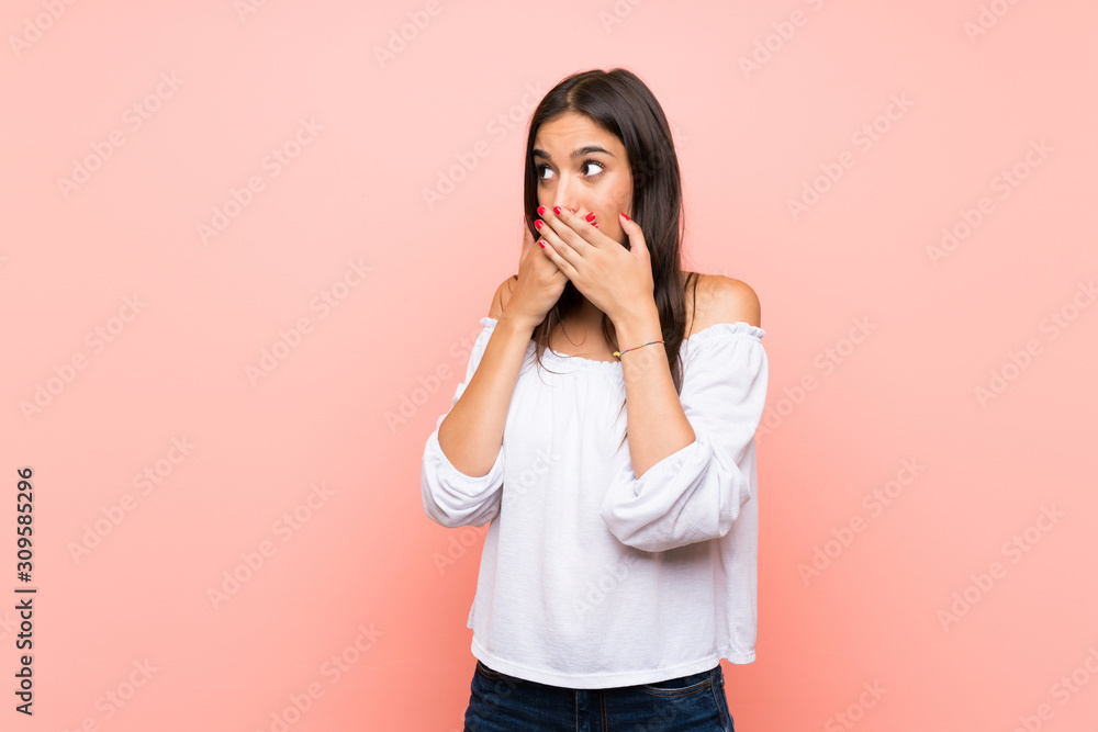 Young woman over isolated pink background covering mouth and looking to the side Young woman over isolated pink background covering mouth and looking to the side