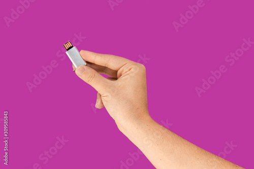Metal pen drive on hand with isolated pink background