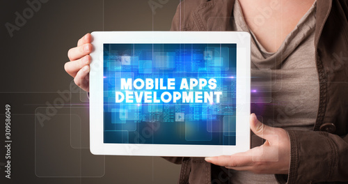 Wallpaper Mural Young business person working on tablet and shows the inscription: MOBILE APPS DEVELOPMENT Torontodigital.ca