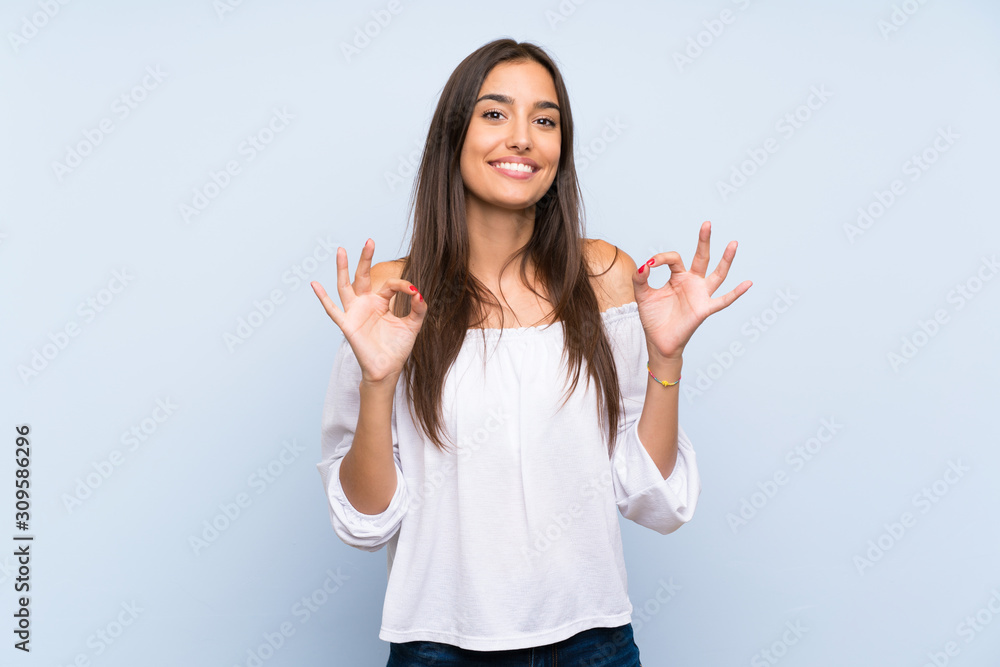 Young woman over isolated blue background showing an ok sign with fingers Young woman over isolated blue background showing an ok sign with fingers