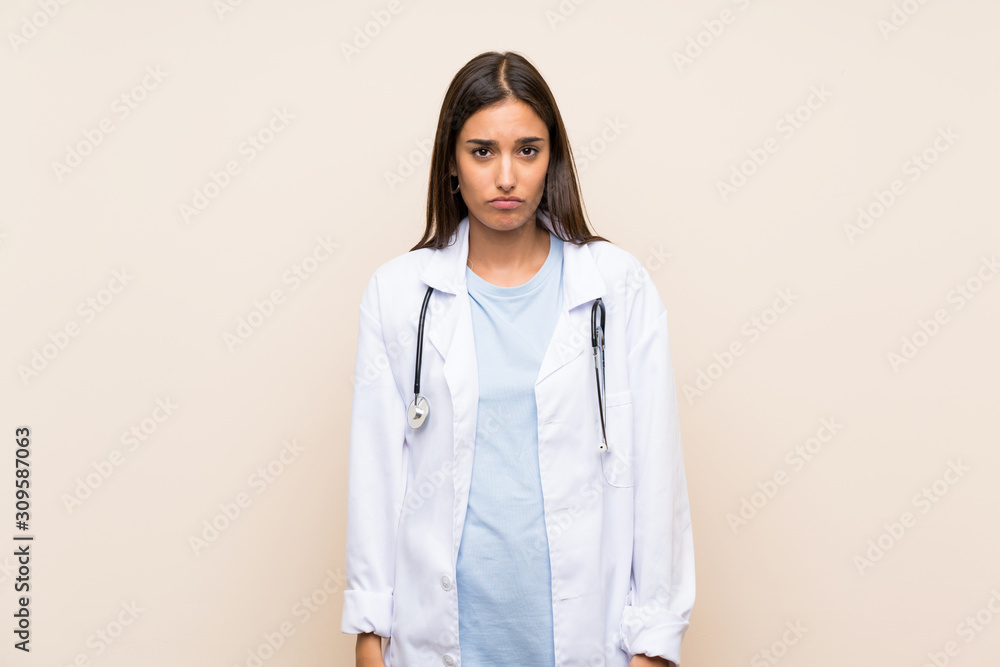 Young doctor woman over isolated background sad